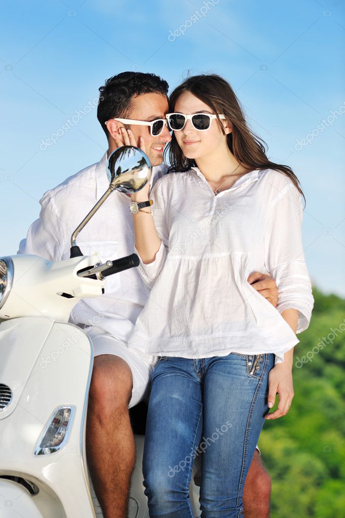 Portrait of happy young love couple on scooter enjoying summer t