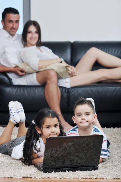 Gelukkig jonge gezin veel plezier en werken op laptop thuis — Stockfoto