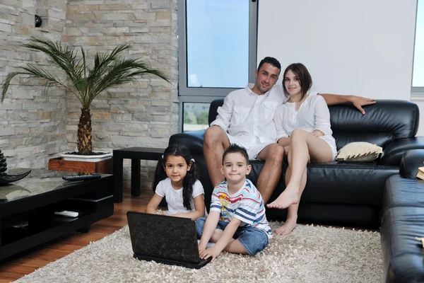 Счастливая молодая семья веселится и работает над ноутбуком дома — стоковое фото