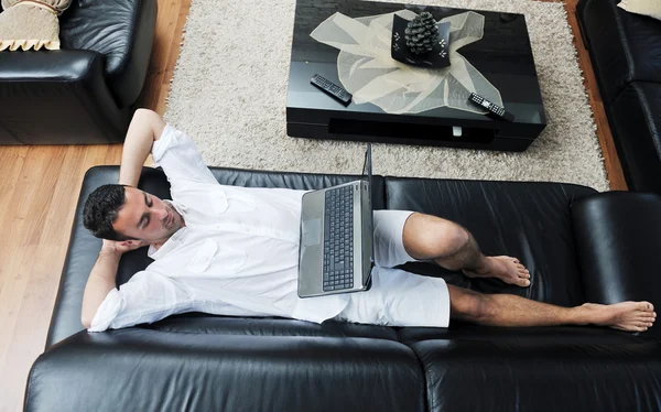 Portret van een ontspannen jonge kerel met behulp van laptop thuis — Stockfoto