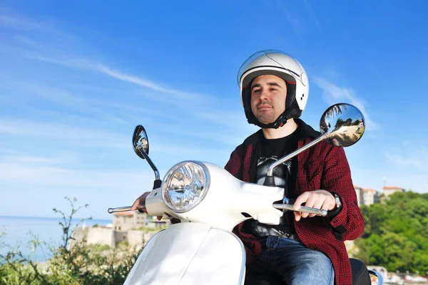Молодой человек катается на ретро-скутере — стоковое фото