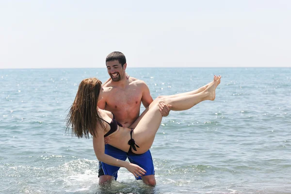 Счастливая молодая пара веселится на пляже — стоковое фото