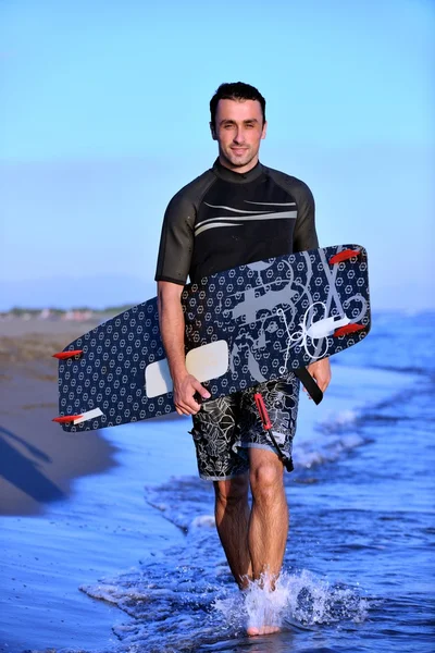 Portret van een jonge kitsurf man op strand op zonsondergang — Stockfoto