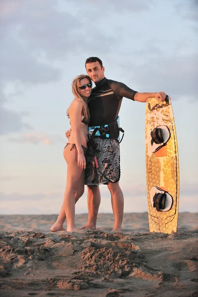 Surf casal posando na praia ao pôr do sol — Fotografia de Stock