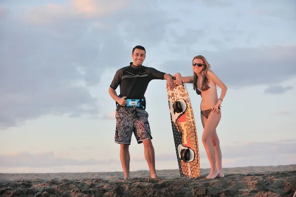 Surf paar poseren op strand op zonsondergang — Stockfoto