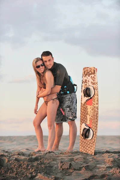 Σερφάρετε ζευγάρι θέτουν στην παραλία στο ηλιοβασίλεμα — Φωτογραφία Αρχείου