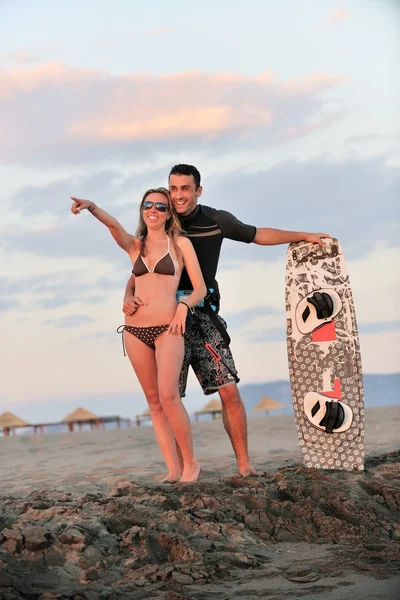 Surf pár pózuje na pláži na sunset — Stock fotografie