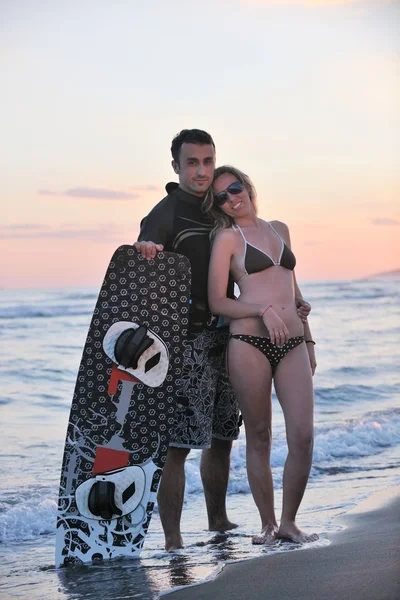 Surf pár pózuje na pláži na sunset — Stock fotografie