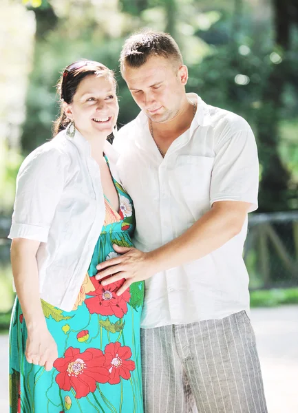 Happy pregnant couple at beautiful sunny day in park — Stock Photo, Image