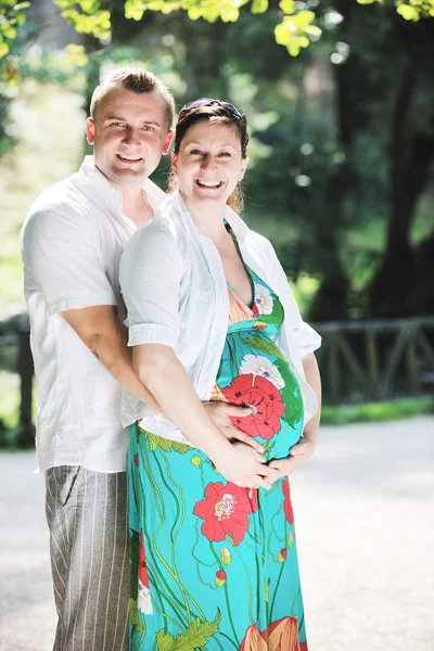 Ευτυχισμένο έγκυος ζευγάρι στο όμορφη ηλιόλουστη μέρα στο πάρκο — Φωτογραφία Αρχείου