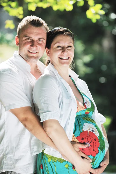 Šťastné těhotné pár na krásný slunečný den v parku — Stock fotografie