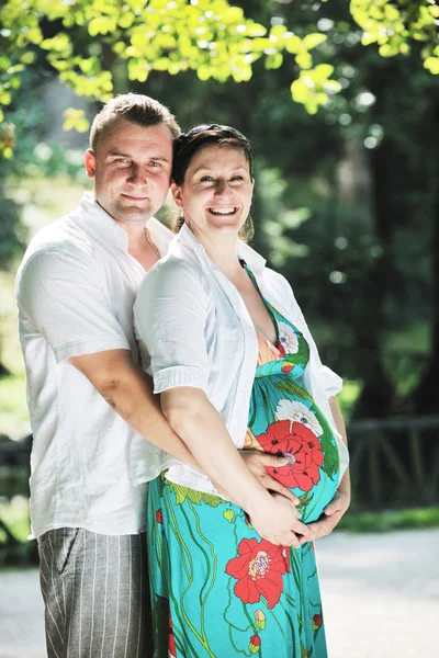 Szczęśliwa para ciąży w piękny słoneczny dzień w parku — Zdjęcie stockowe