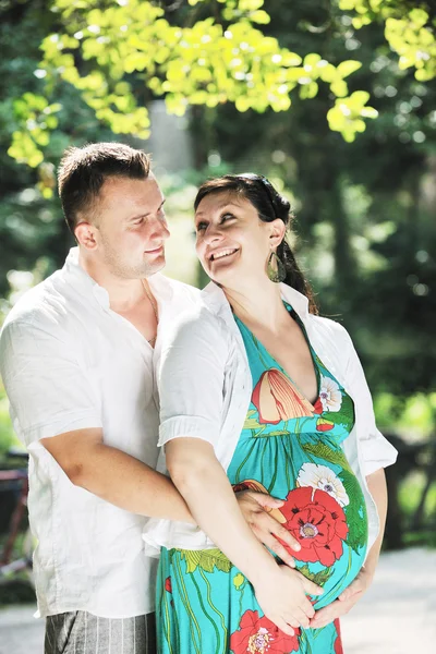 Šťastné těhotné pár na krásný slunečný den v parku — Stock fotografie