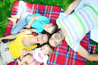 Happy young couple with their children have fun at park clipart