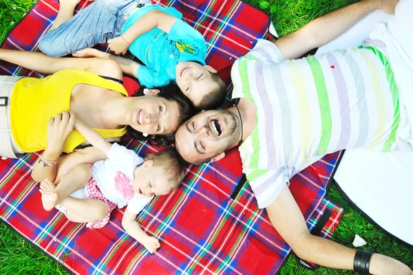 Lyckliga unga par med sina barn ha roligt på park — Stockfoto