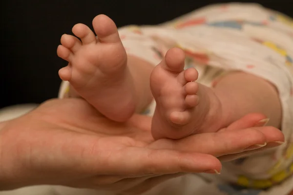 Pernas de bebê na mão mãe — Fotografia de Stock