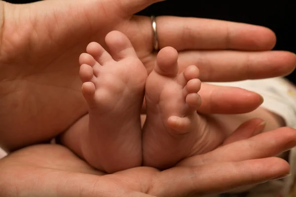 Patas de bebé en manos de madre — Foto de Stock
