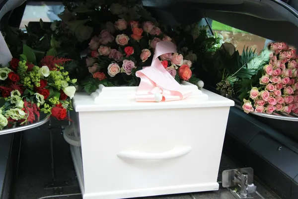 Cercueil blanc dans un corbillard gris — Photo