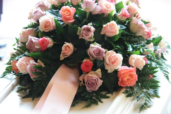Pink sympathy flowers on a white coffin — Stock Photo, Image