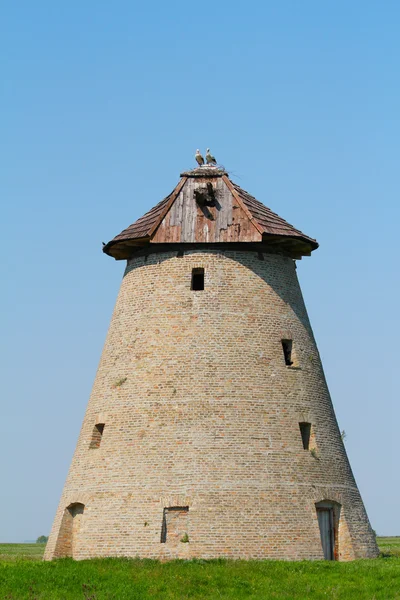 Starý větrný mlýn s Čapí hnízdo na střeše — Stock fotografie