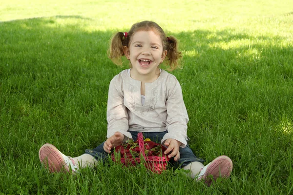 Happy young girl sitting on grass in park — Stock Photo, Image