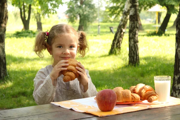 Jong meisje eten croissant — Stockfoto