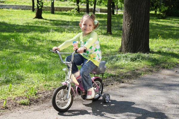 Young girl riding bicycle in park — Stock Photo, Image
