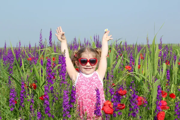 Счастливая маленькая девочка, стоящая на ярком лугу — стоковое фото
