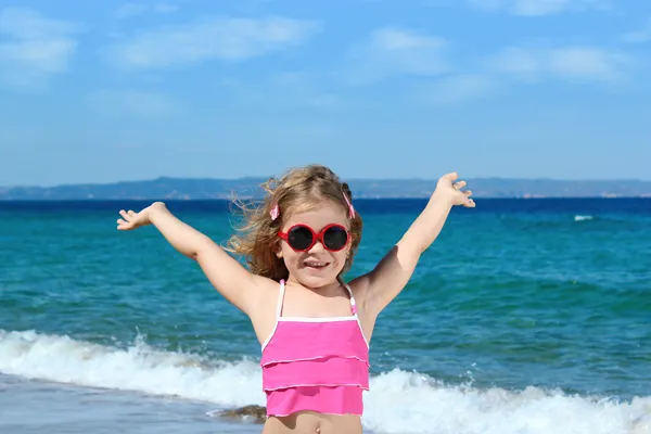 Счастливая маленькая девочка в солнечных очках на пляже — стоковое фото