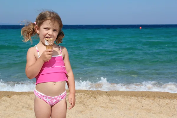 小さな女の子はビーチでアイスクリームを食べる — ストック写真