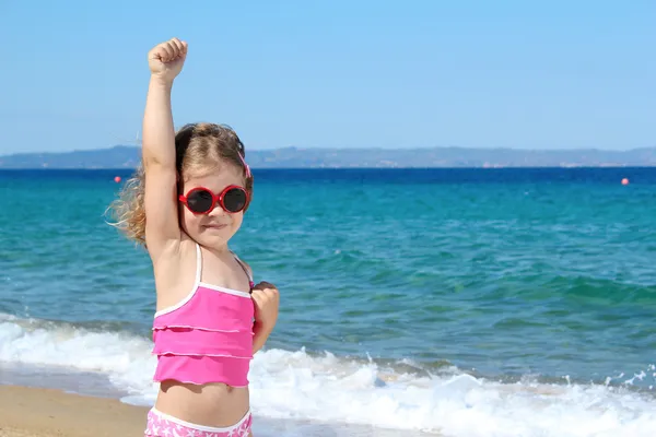举手的姿势在海滩上的小女孩 — 图库照片