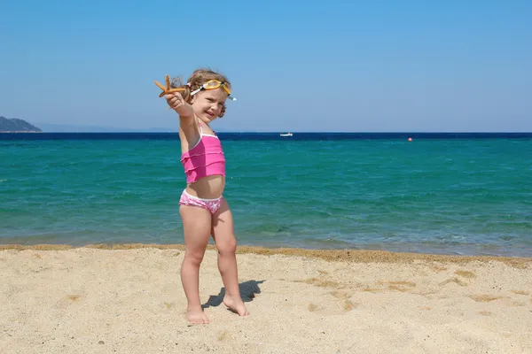 Bambina con stelle marine e occhiali sulla spiaggia — Foto Stock