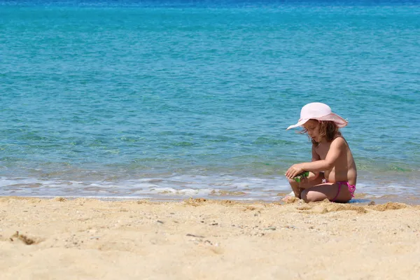 Menina com chapéu de palha brincando na praia — Fotografia de Stock