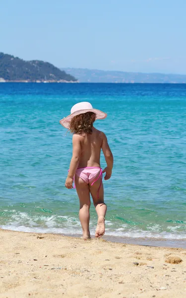 Маленькая девочка в соломенной шляпе ходит по пляжу — стоковое фото