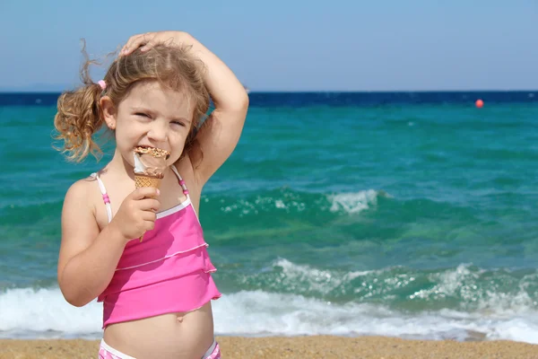 Молодая девушка с мороженым на пляже — стоковое фото