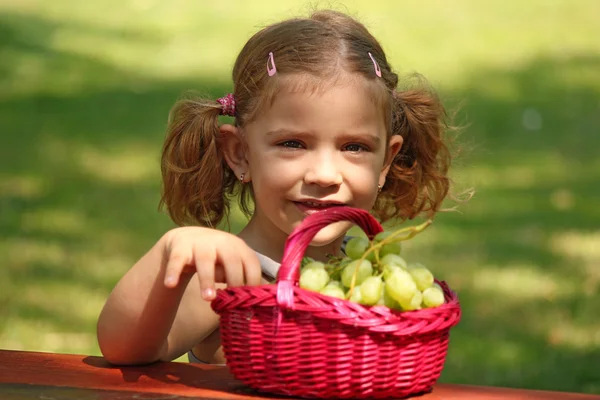 小さな女の子がブドウを食べる — ストック写真