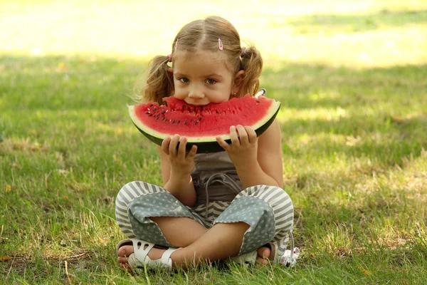 Menina come melancia no parque — Fotografia de Stock