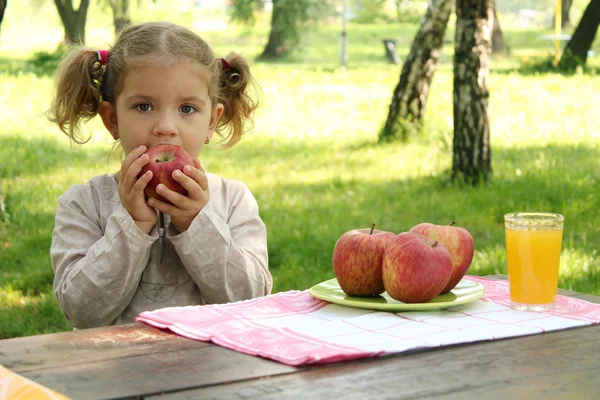 La bambina mangia la mela nel parco — Foto Stock