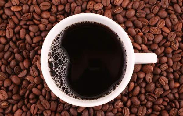 Xícara de café e grãos no fundo — Fotografia de Stock