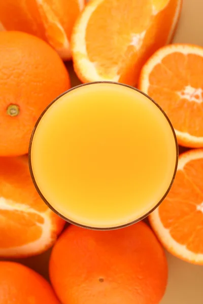 Zumo de naranja y naranjas maduras sobre fondo — Foto de Stock