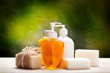 Liquid soap and soap bars on green background clipart