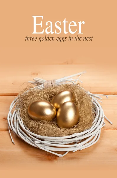 Easter eggs - three golden eggs in the nest — Stock Photo, Image