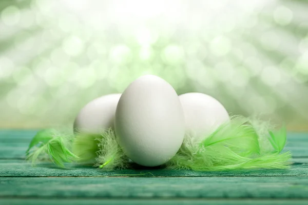 Tres huevos blancos y plumas verdes — Foto de Stock