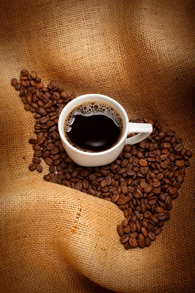 Чашка еспрессо та кавових зерен на фоні джуту — стокове фото