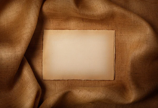 Tło - stary arkusz papieru na tle juty — Zdjęcie stockowe