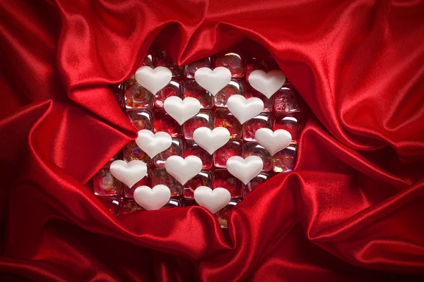 День Святого Валентина - білі серця на червоному атласі — стокове фото