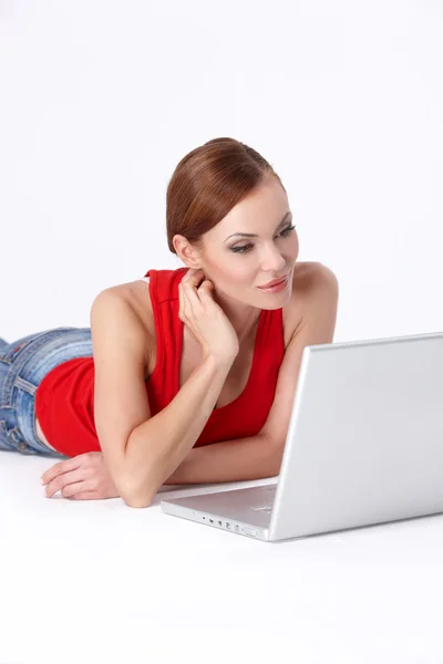 Ładny żeński kłamliwy w dół i za pomocą laptopa — Zdjęcie stockowe