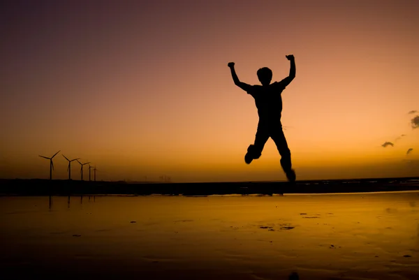 O homem animado Saltar na praia sob o pôr do sol — Fotografia de Stock