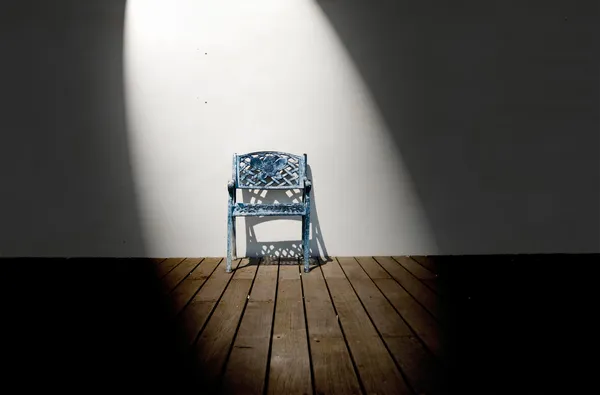 Spotlight on single iron chair on wooden floor — Stock Photo, Image
