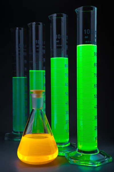 Green in cylinders yellow flask — Stock Photo, Image